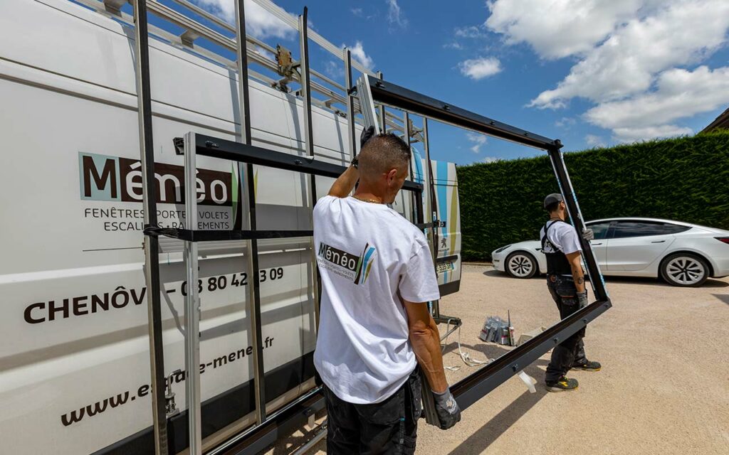 Employés de Ménéo transportant un cadre de fenêtre